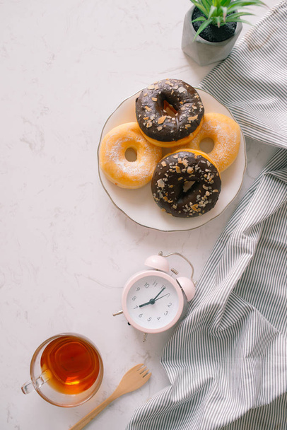 Overhead view of chocolate cake donuts with salted caramel glaze with a cup of espresso on marble table top. Afternoon me time book reading with dessert and coffee. Text space images - 写真・画像