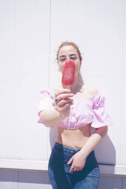 photo of young cute woman in pink shirt and glasses holding frozen ice-cream outdoor in sunny day - Photo, Image
