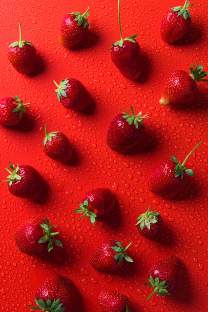 top view of strawberries on red surface with water drops - Foto, immagini