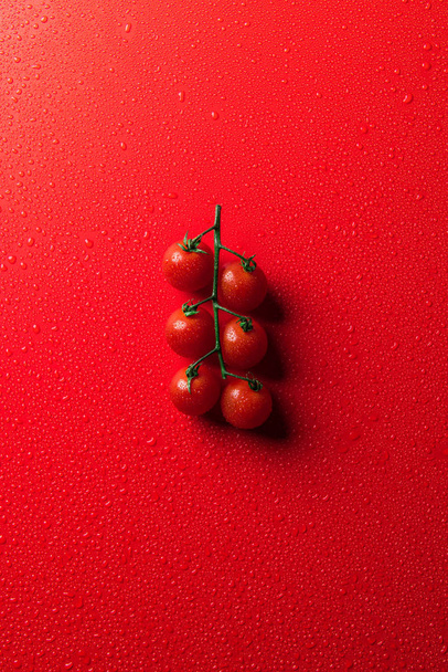 vista superior de tomates cherry en la superficie roja con gotas de agua
 - Foto, imagen