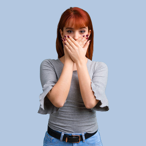 Jeune fille rousse couvrant la bouche avec les mains sur fond bleu
 - Photo, image