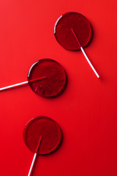 top view of three lollipops on red surface - Foto, Bild