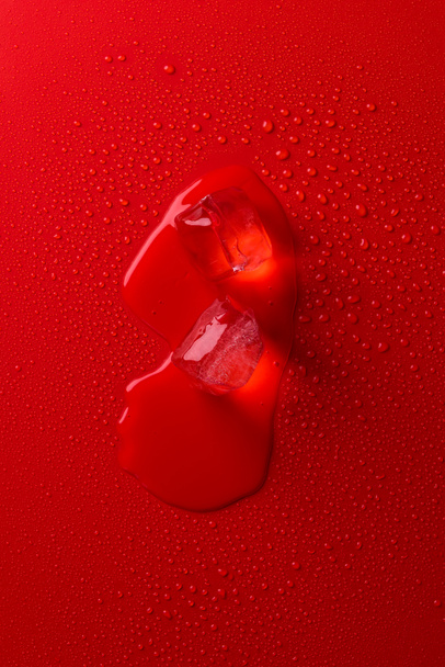 vista superior de la fusión de cubitos de hielo en la superficie roja con gotas de agua
 - Foto, Imagen