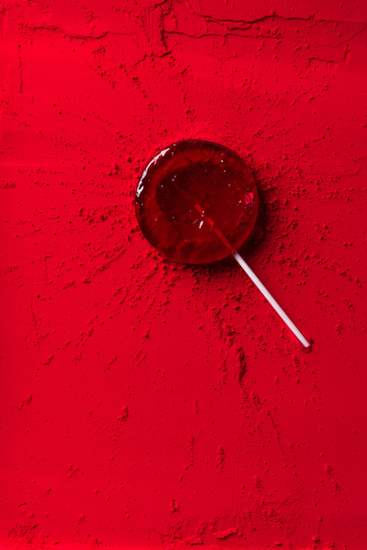 top view of red lollipop on red powder - Foto, Bild