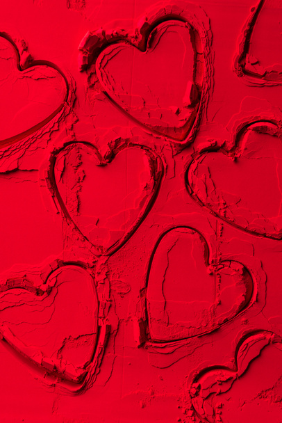 top view of shapes of cookie cutters in shape of hearts on red powder - Photo, Image