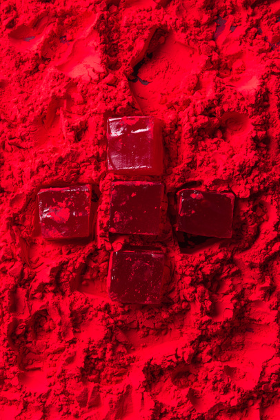 top view of candies in shape of cross on red powder - Photo, Image
