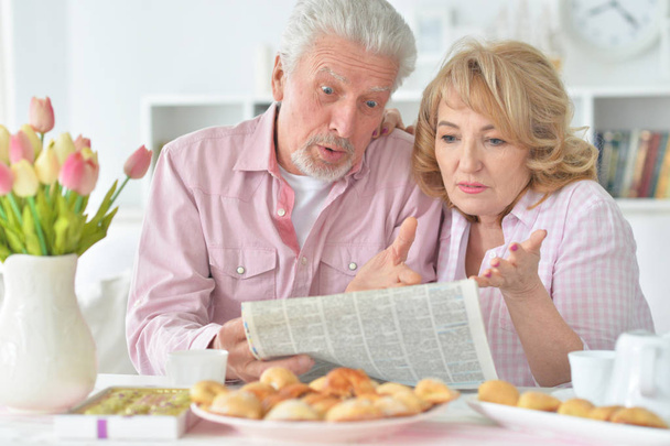 Close-up portrait of a  senior couple with newspaper  at home  - Photo, image