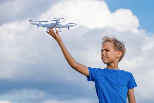 Ребенок держит дрон на открытом воздухе в летний день
 - Фото, изображение