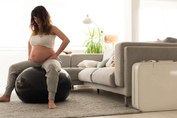 Pregnant woman doing relax exercises with a fitness pilates ball at home - Foto, Imagem