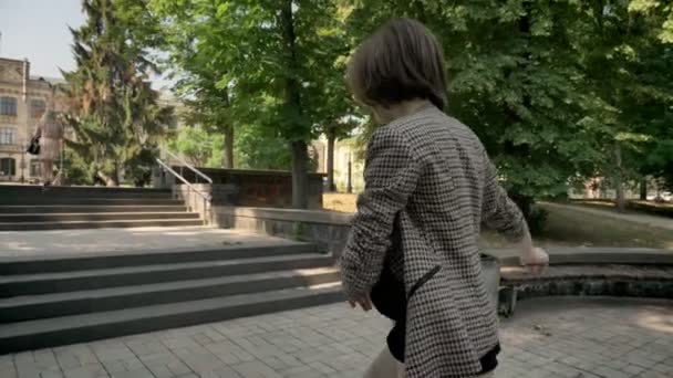 Silhouette of young cute girl is dancing on stairs in park in daytime, in summer, movement concept, back view, side view, dolly shot - Záběry, video