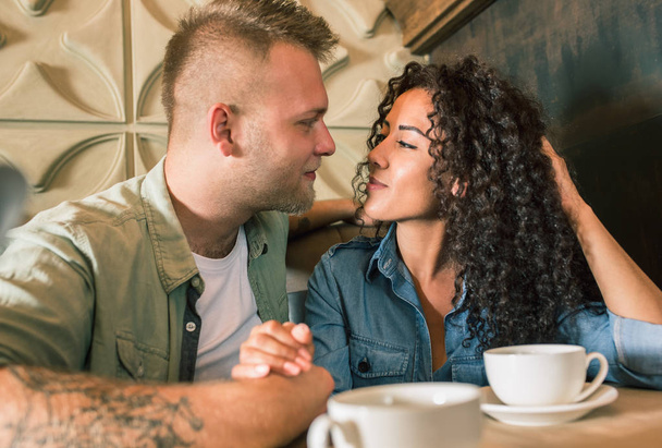 Happy young couple is drinking coffee and smiling while sitting at the cafe - Photo, image