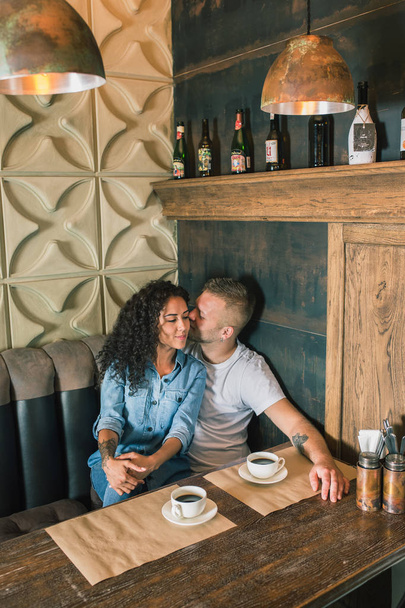 Happy young couple is drinking coffee and smiling while sitting at the cafe - Foto, Imagen