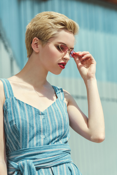 girl with short hair posing in trendy blue dress and pink sunglasses - Fotografie, Obrázek