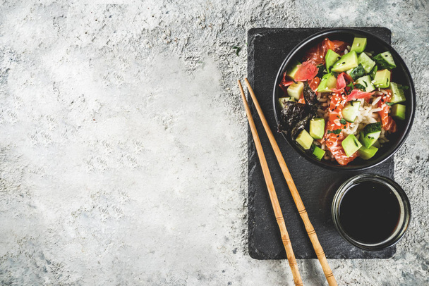 Comida de moda asiática, tazón de sushi poke con pepino, salmón, aguacate, semillas de sésamo blanco y negro
 - Foto, imagen
