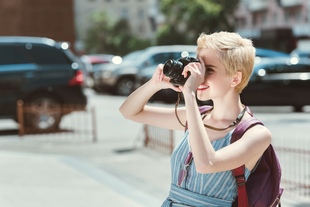 traveler with backpack taking photo on camera in city - 写真・画像