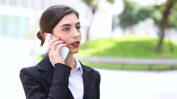 Business woman using her mobile phone in front of her office - Footage, Video