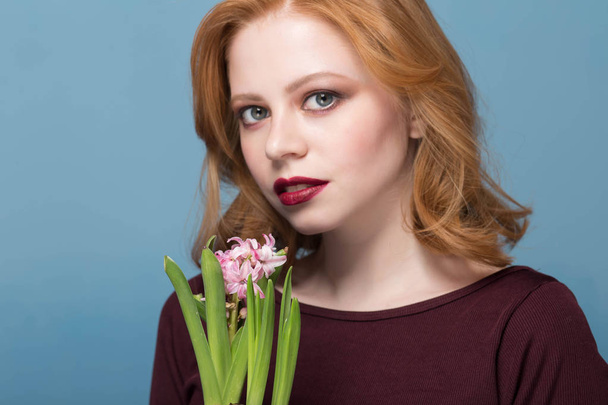 Close up portrait of a young woman smelling hyacinth. Flowers in the foreground in focus - Foto, Imagen