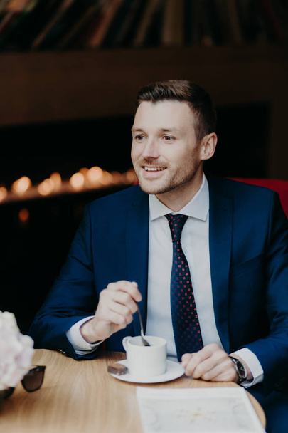 handsome young businessman in suit drinking coffee in cafe. Leisure and business concept  - Foto, afbeelding