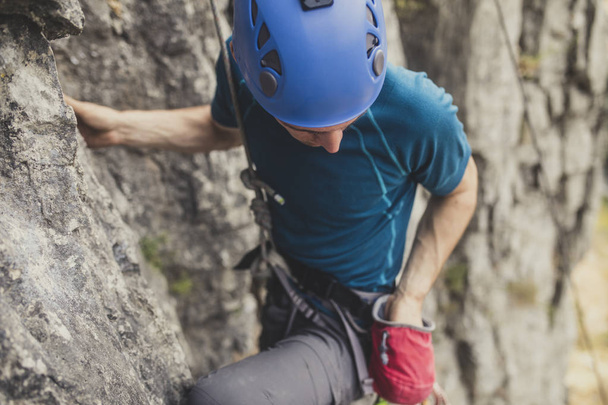 A man climbing an outdoor natural rock. - Фото, изображение