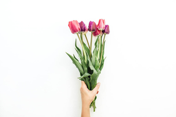 Ženská ruka drží kytici tulipánů na bílém. Plochá ležel, horní pohled květiny slavnostní pozadí. - Fotografie, Obrázek