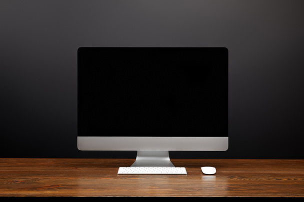 close up view of designer workplace with blank computer screen and computer mouse on wooden tabletop - Photo, Image