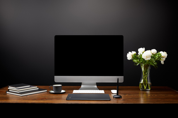 Vista de primer plano del lugar de trabajo del diseñador gráfico con tableta gráfica, pantalla de computadora en blanco, cuadernos y taza de café en la mesa de madera
 - Foto, imagen