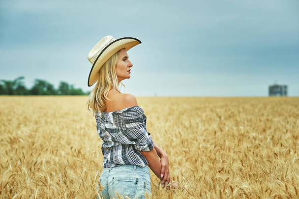 Jeune femme en vêtements décontractés pour une promenade dans les champs avec du blé
 . - Photo, image