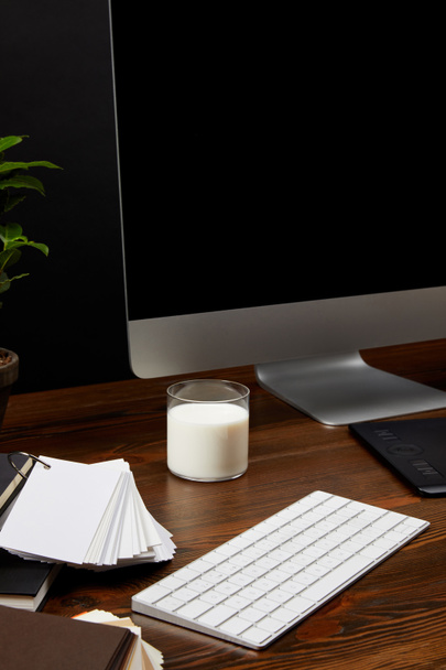 Close-up van ontwerper werkplek met glas melk, scherm en toetsenbord op houten tafelblad - Foto, afbeelding