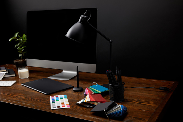 close up view of graphic designer workplace with colorful pallet, graphic tablet, computer screen and lamp on wooden surface - Fotografie, Obrázek