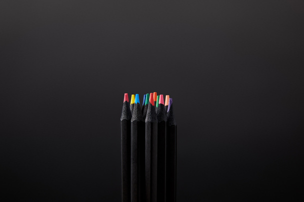 Close-up van gearrangeerde potloden op zwarte muur achtergrond - Foto, afbeelding