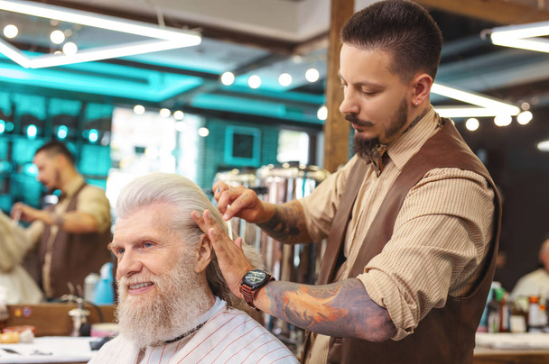 Competent barber serving his mature client - Zdjęcie, obraz