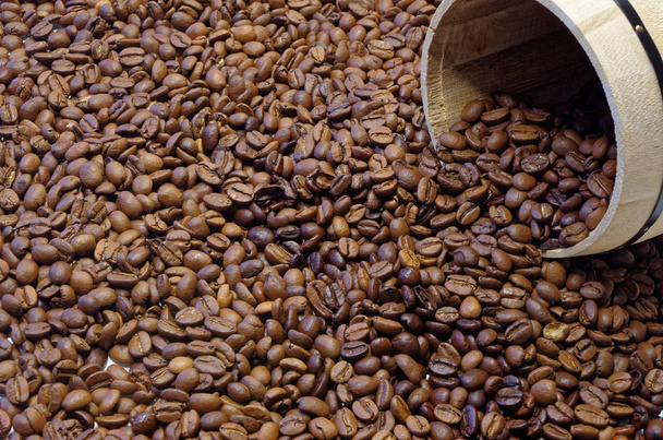 Roasted coffee beans as a background and a part of wooden box in the corner of the picture  - Photo, Image