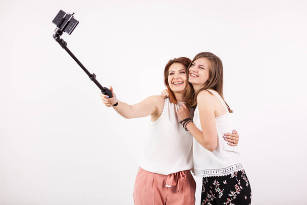 Deux belles jeunes femmes prenant un selfie avec un bâton de selfie
 - Photo, image