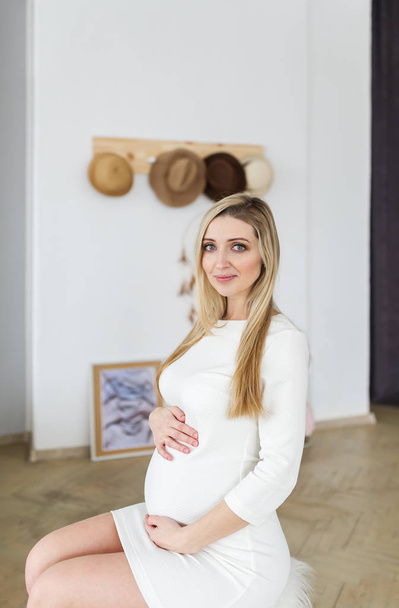 Портрет вагітної блондинки на домашньому тлі
. - Фото, зображення