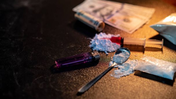 Drug injection syringe on heroin powder. Spoon with cigarette lighter for heroin cooking and money on dark table. Drug addiction concept - Fotoğraf, Görsel