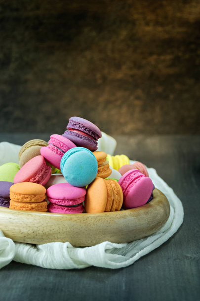 colorful of macarons on plate over wooden table - Foto, afbeelding