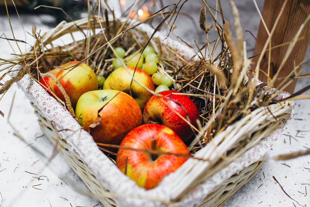 Rode appels in een rieten mand met stro. Picknick in het bos - Foto, afbeelding