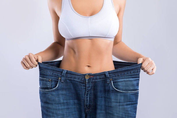 Woman after weight-loss trying her old jeans - Foto, imagen
