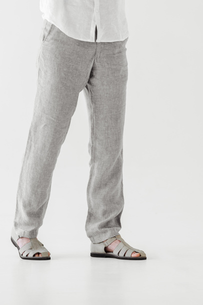 abgeschnittenes Bild eines männlichen Modells in Leinenhosen und Sandalen isoliert auf grauem Hintergrund  - Foto, Bild