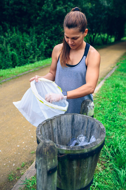 Γυναίκα ρίχνει σκουπίδια μετά από plogging - Φωτογραφία, εικόνα