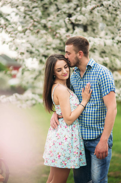 恋咲く庭で休んで若いカップル。白い花咲く木 - 写真・画像