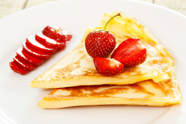 Pancakes with strawberries on white plate, close up - Fotó, kép