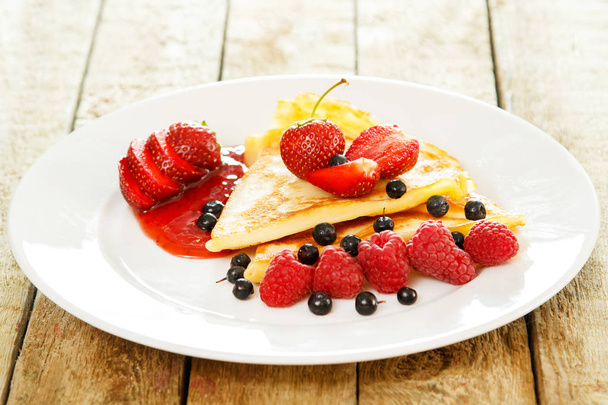 Pancakes with berries in white plate, close up view  - Fotó, kép