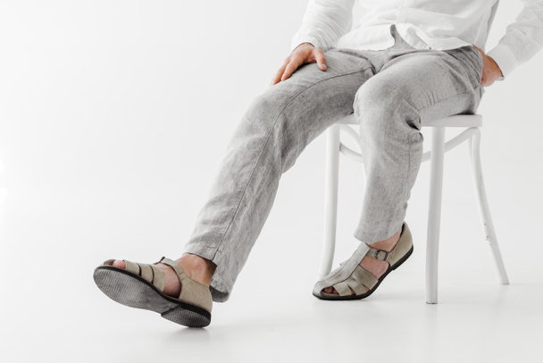 обрезанное изображение мужской модели в льняной одежде, сидящей на стуле изолированно на сером фоне
  - Фото, изображение