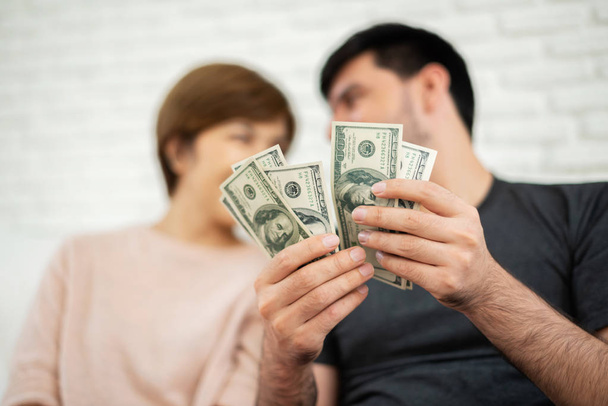 Happy Young couple counting money while sitting on sofa for their new house. Saving. - 写真・画像