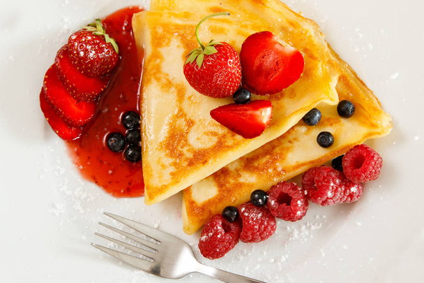 Pancakes with berries and sugar powder on the plate - Fotó, kép