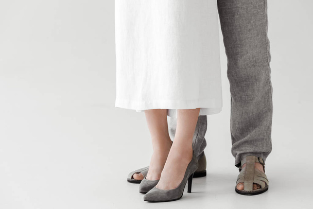 cropped image of legs of couple of models in linen dress and trousers isolated on grey background  - Photo, Image