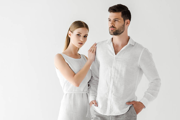 attractive woman in linen white dress embracing boyfriend with hands in pockets isolated on grey background - Photo, Image