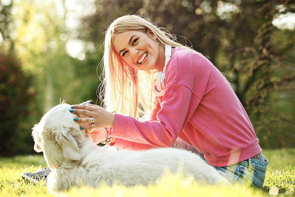 junge blonde Frau entspannt mit ihrem Retriever im Park. - Foto, Bild