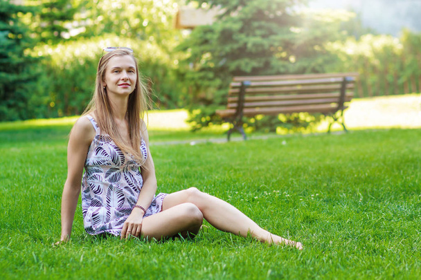 Retrato de una mujer bonita, joven y alegre sentada sobre hierba verde y descansa
 - Foto, imagen